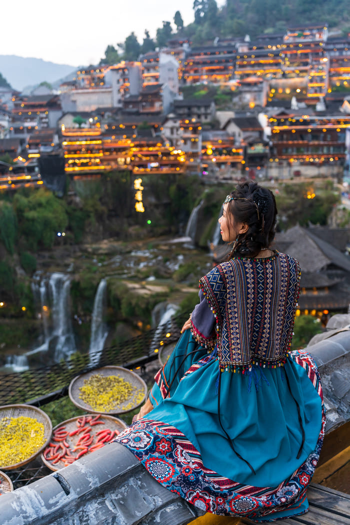 Mujer viendo el paisaje en china abajo de ella platos con comida
